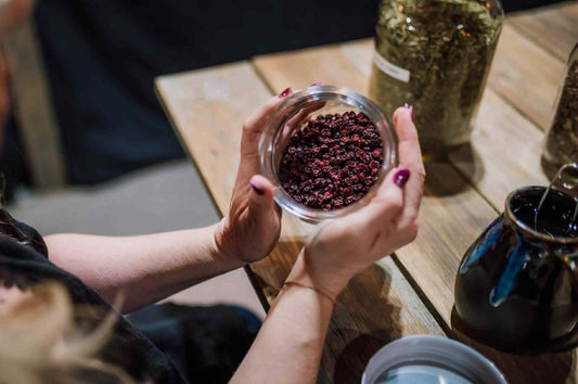 A photo of Angie's hands holding a jar of hibiscus tea cupped around the jar sides to show how Intuitive Herbalism is more about connecting with plants